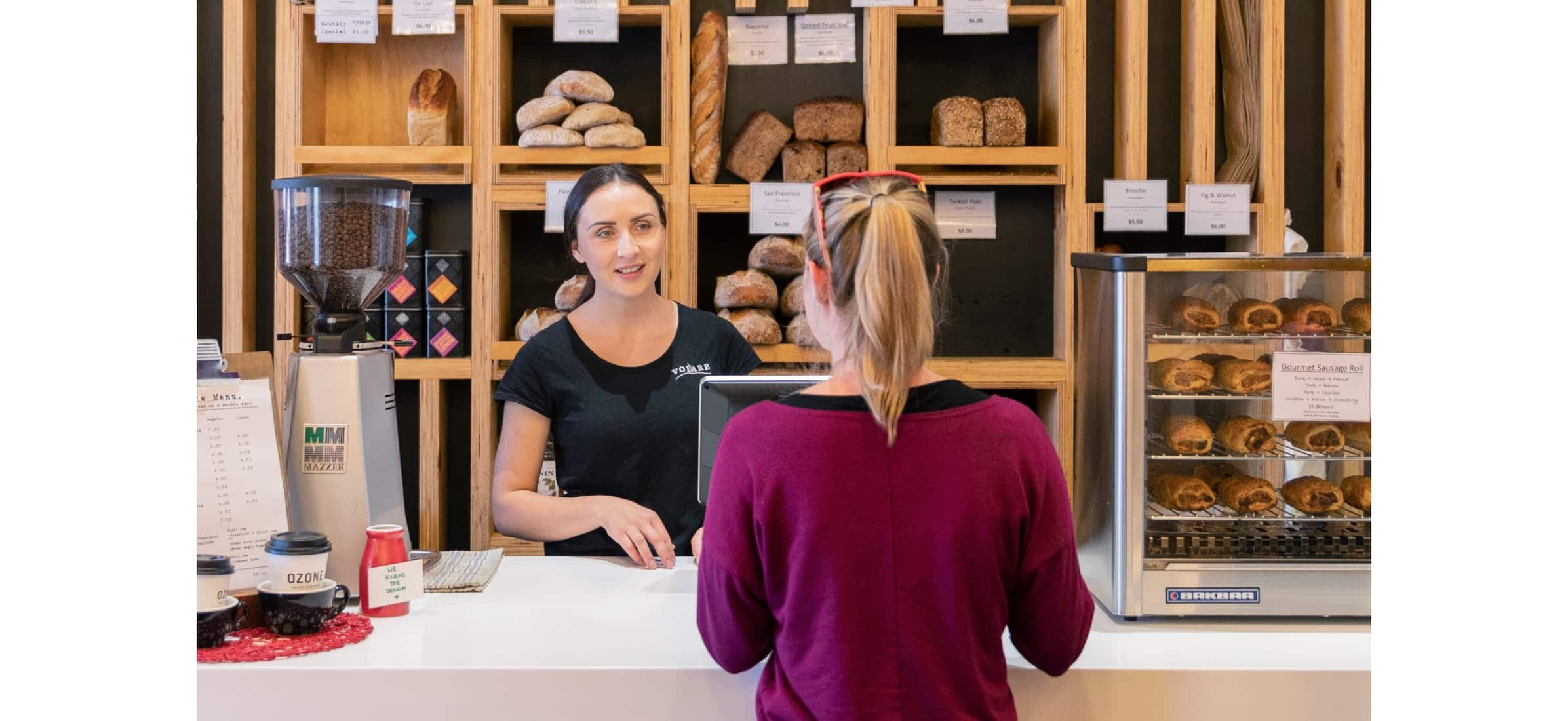 A member of Volare staff serves a customer at the bakery shop.